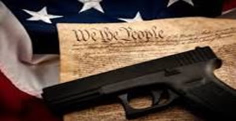 The US Constitution on top of an American flag with a handgun on top.