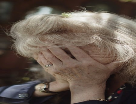 A distraught older woman with her head in her hands.